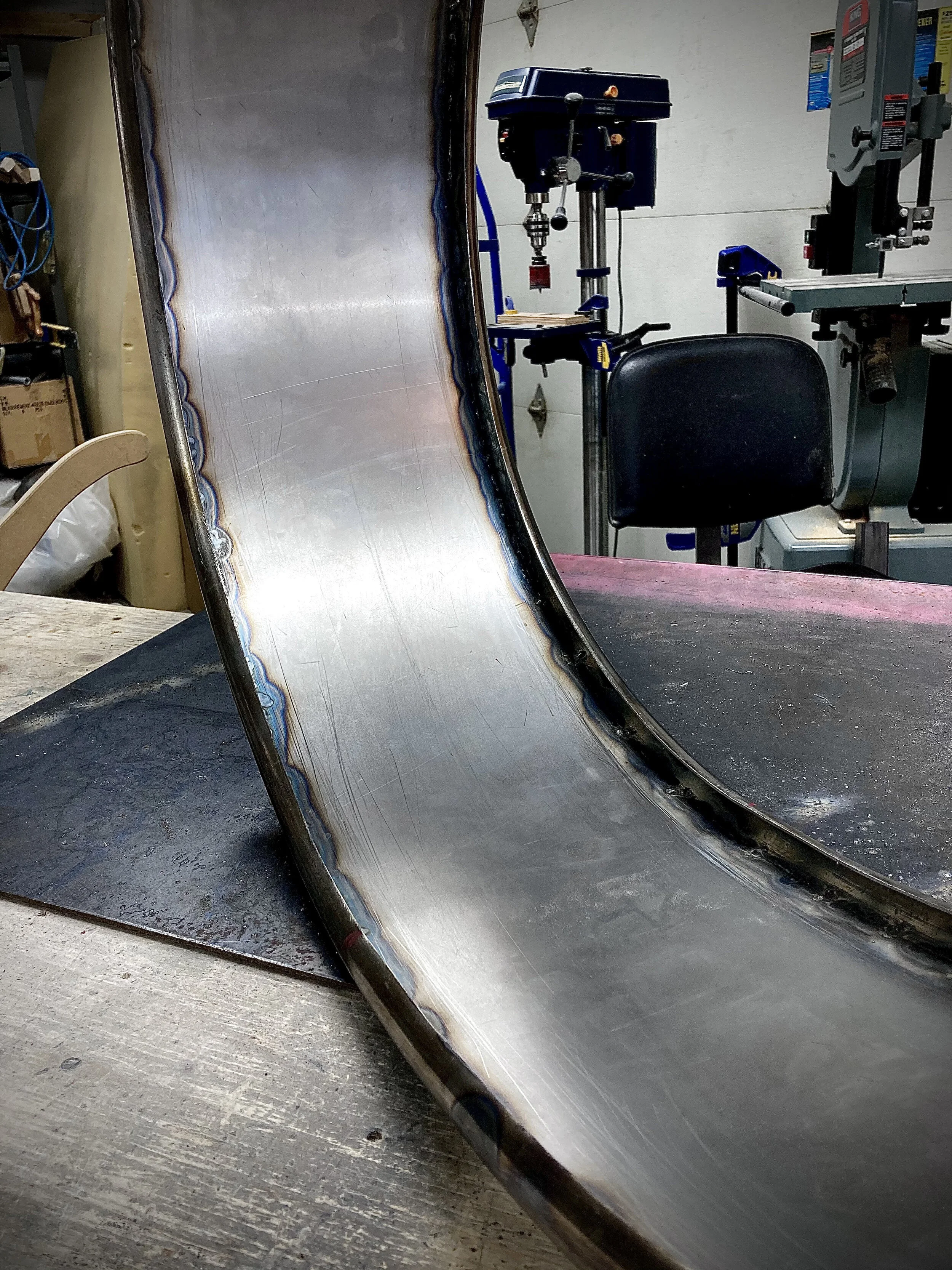 For the rounded edges, I bent a 1" tube to the shape of the sign and cut it down the middle to give me two halves. These halves were then tacked in place to the flat sheet metal.