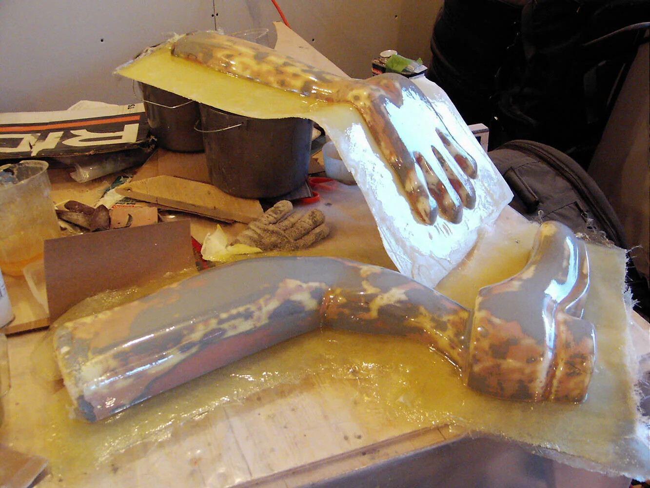 Here are the master plugs for hands and feet being made by fiberglassing over the carved foam shapes.